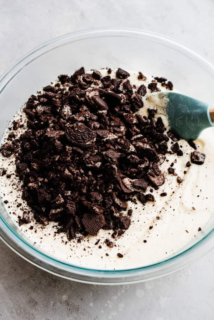 Oreo pieces sitting on top of the batter in a large mixing bowl.