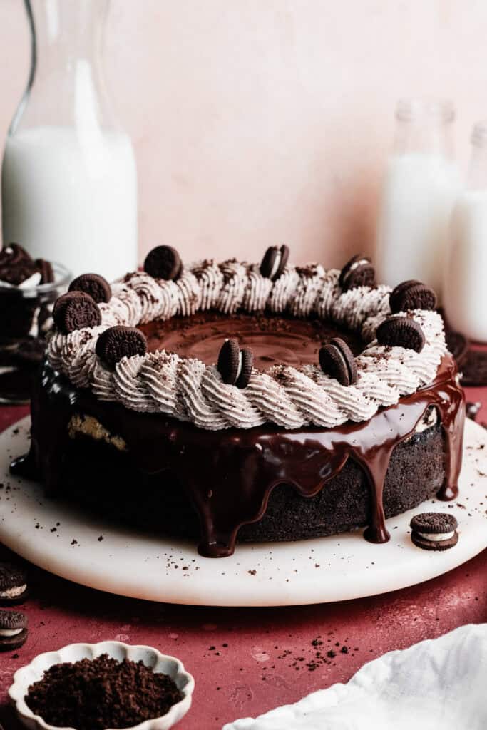 The full, finished cheesecake, topped with a chocolate ganache drip, oreo whipped cream, and mini oreos.