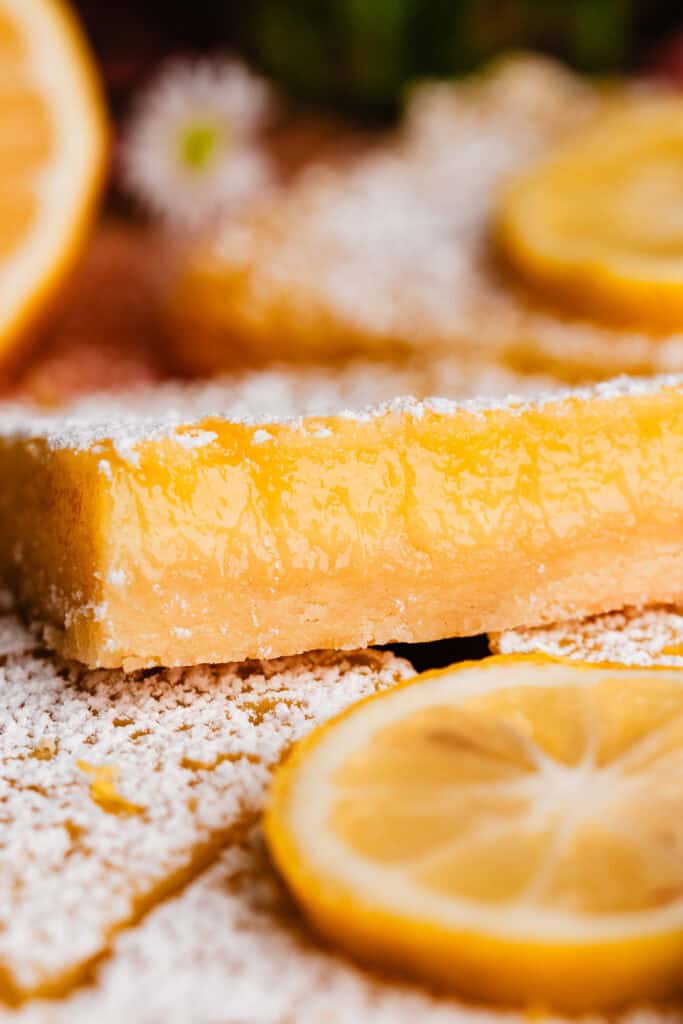 A close-up on a cross section of one of the lemon bars, showing the crisp crust and creamy lemon filling.