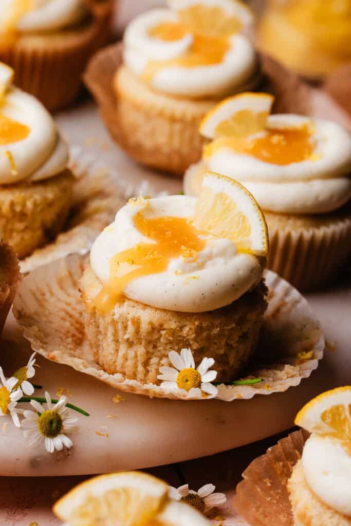 Lemon Cupcakes on a marble cake plate, topped with lemon cream cheese frosting and extra lemon curd.