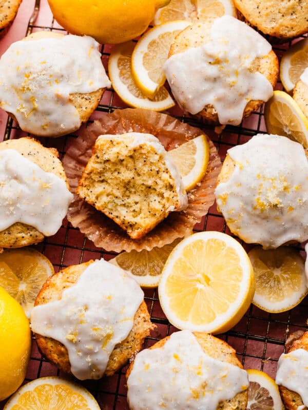 A bird's eye view of the lemon glazed lemon poppyseed muffins on a cooling rack, set over a pink surface.