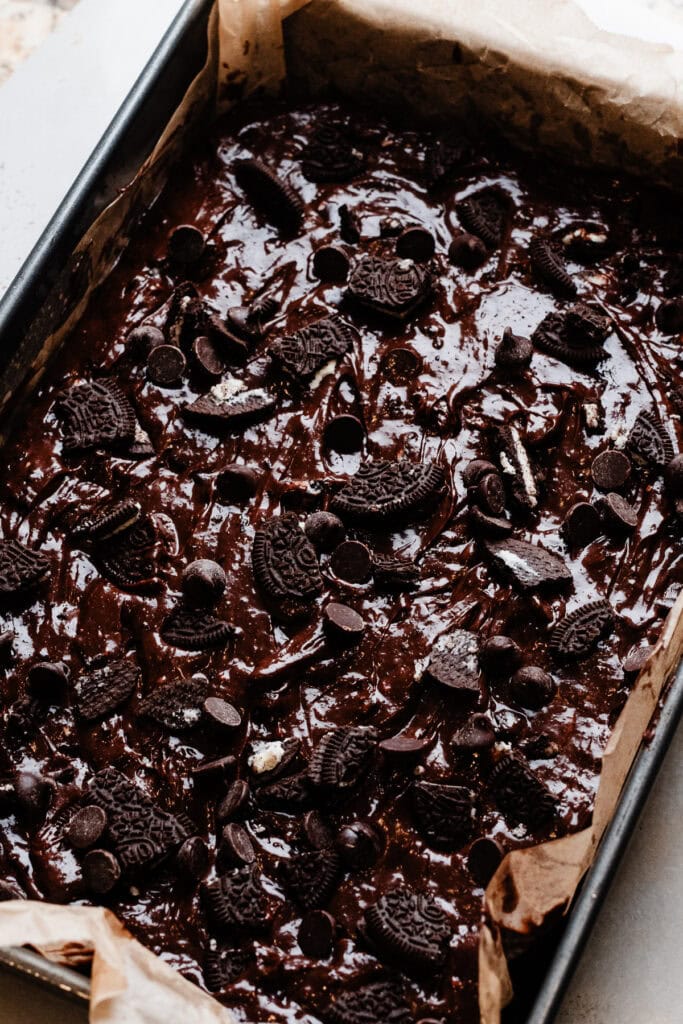 The oreo brownie batter spread in a 9x13 pan, ready to be baked.