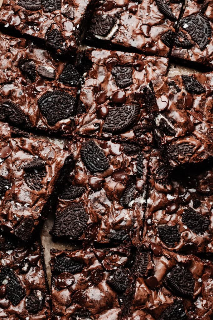 A bird's eye view of the sliced brownies, with oreo pieces and chocolate chips visible on top of the shiny crust.