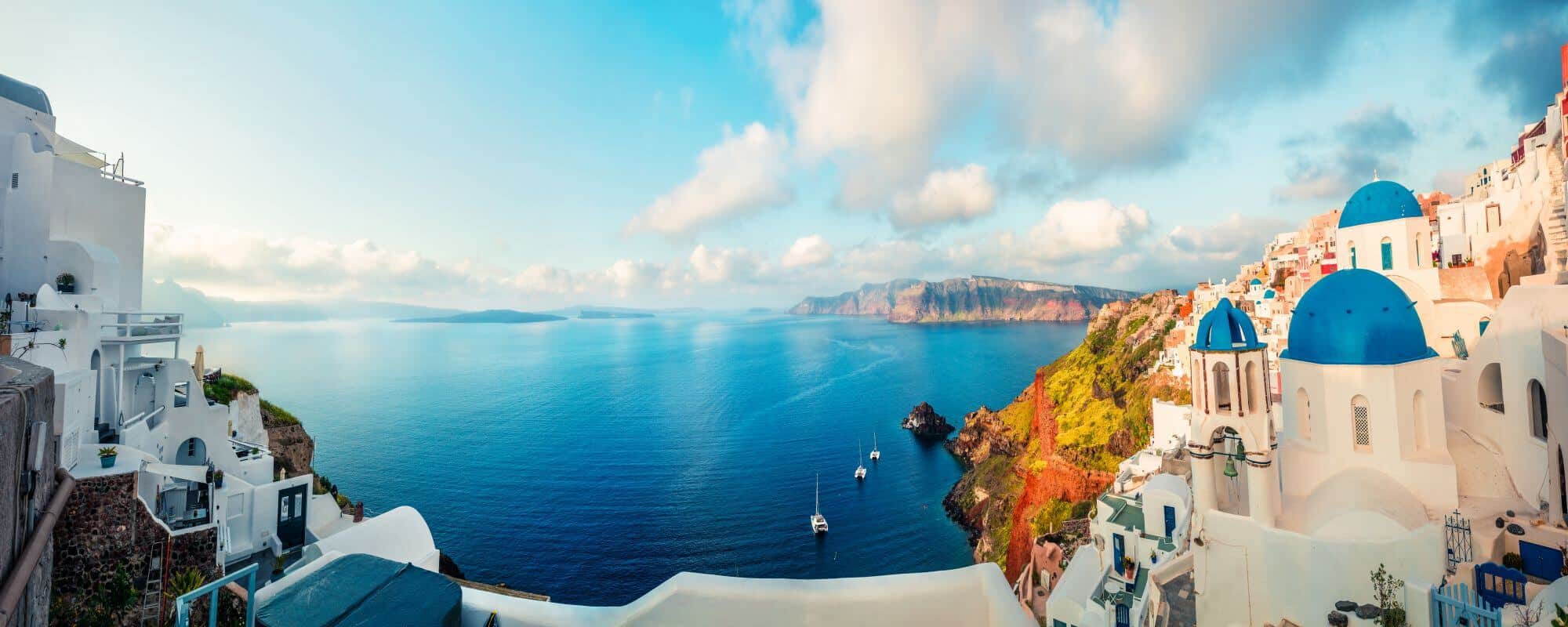Scenic view of Santorini coast with white buildings and blue domes overlooking the sea.