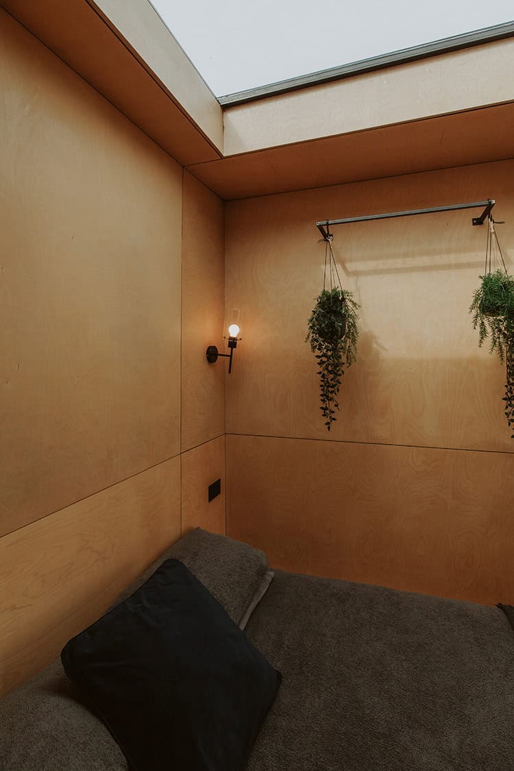 Eco-friendly off-grid tiny home interior with minimalist design, natural wood walls, indoor plants, and cozy sleeping area. Perfect for sustainable living and off-grid adventures.