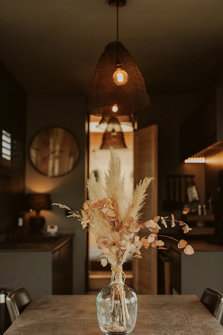 Wildflower arrangement in a glass vase on a rustic table inside a cosy off-grid cabin, featuring warm lighting and natural decor for a peaceful off-grid stay.