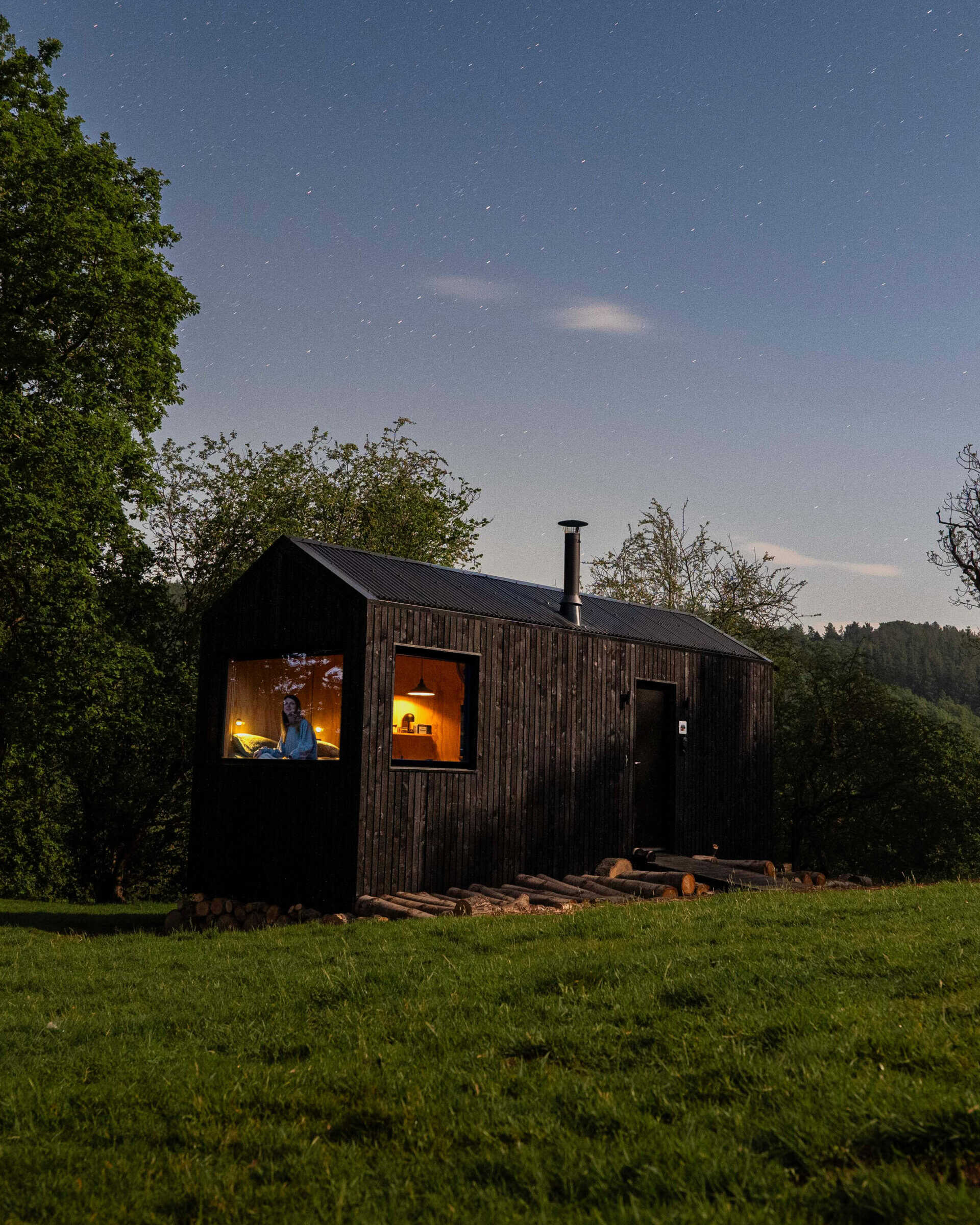 Cozy off-grid tiny house at night under starry sky, eco-friendly living, off-grid cabin, sustainable rural retreat, solar-powered hideaway, peaceful wilderness escape, natural living advantages.