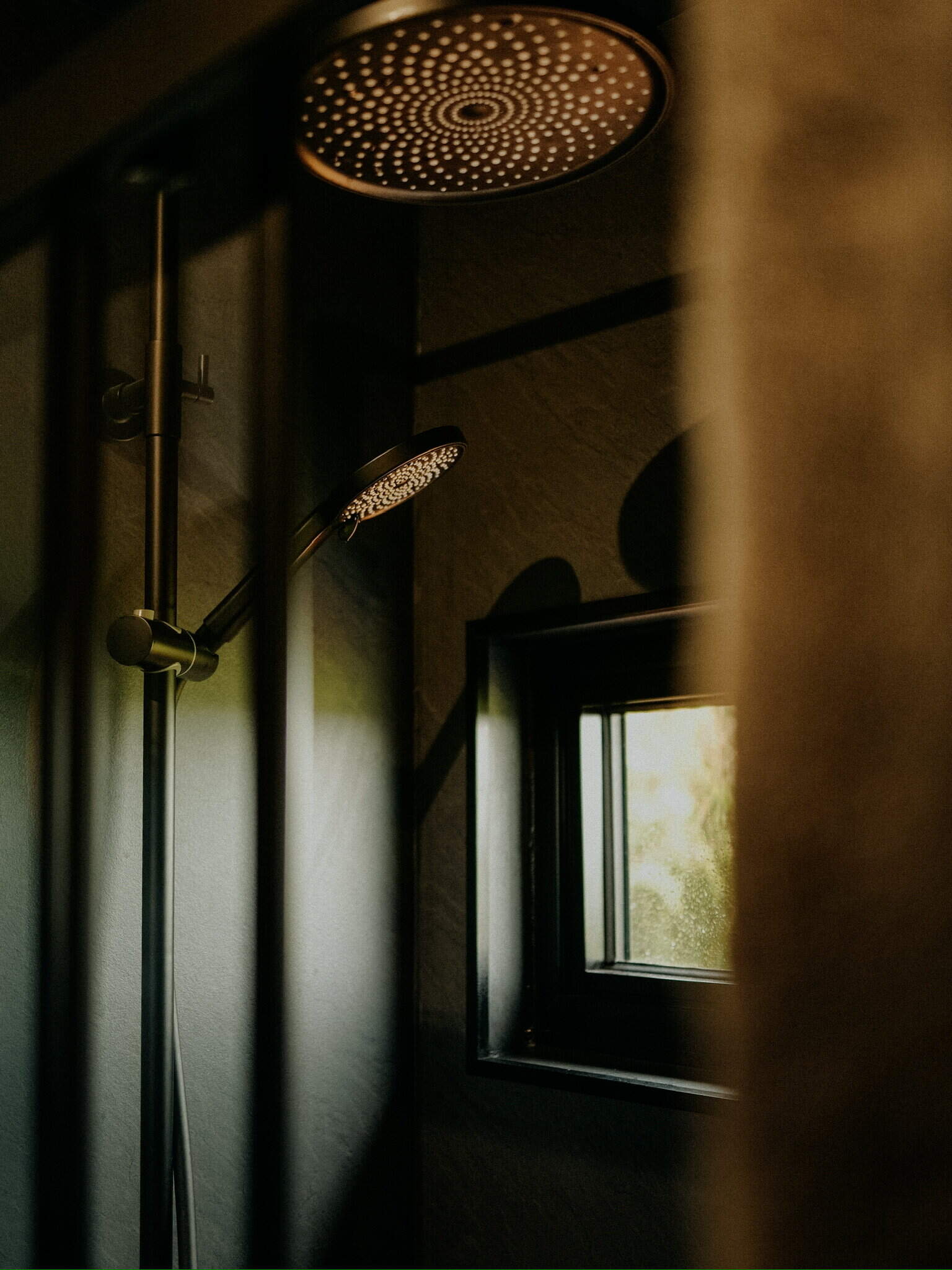 Shower head and window in a modern off-grid bathroom, showcasing sustainable living and eco-friendly bathroom design for off-grid lifestyle.