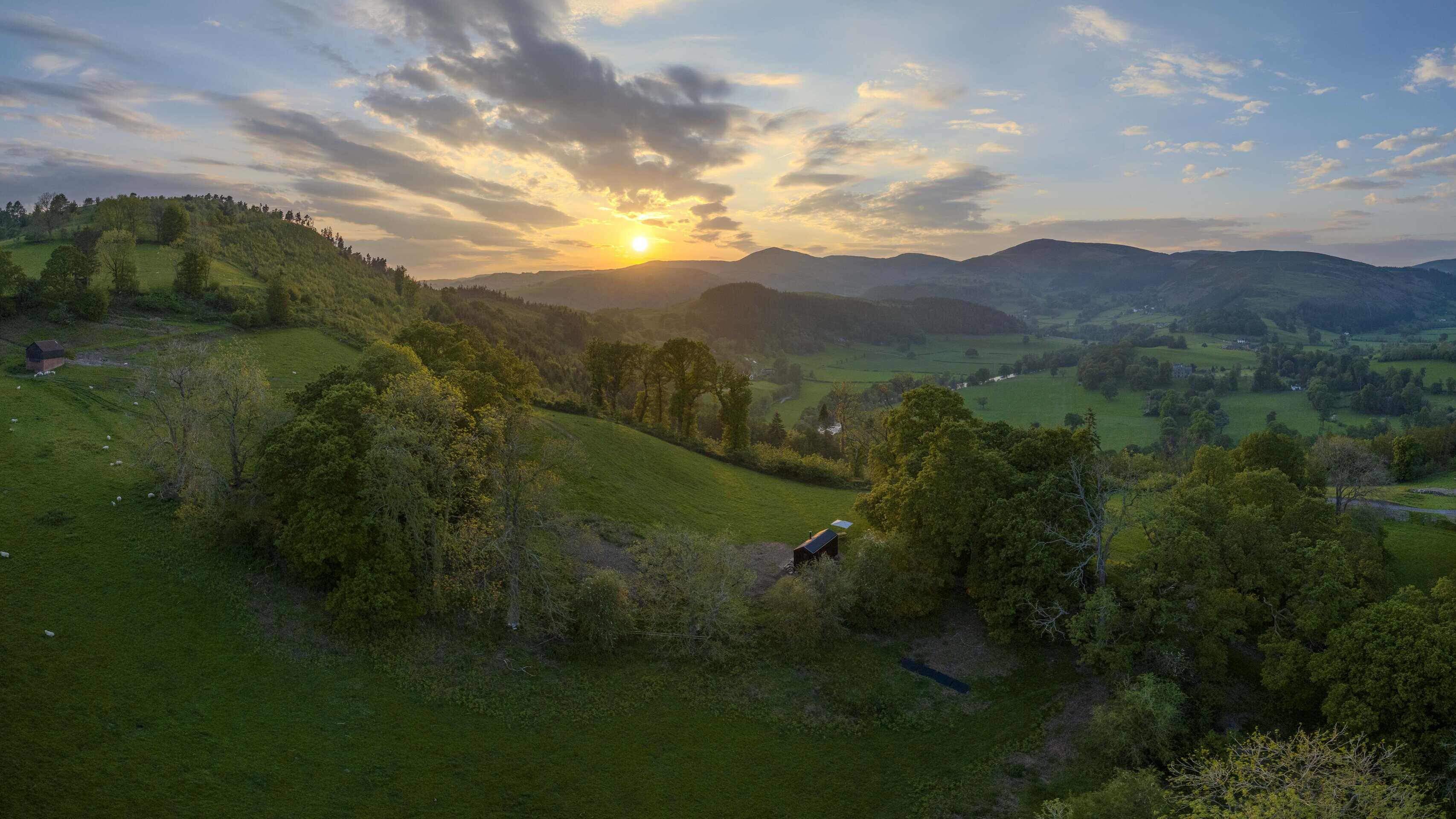 Secluded off-grid cabin nestled in lush green countryside at sunset, showcasing sustainable living and off-grid lifestyle in rural UK. Perfect for eco-conscious escape.