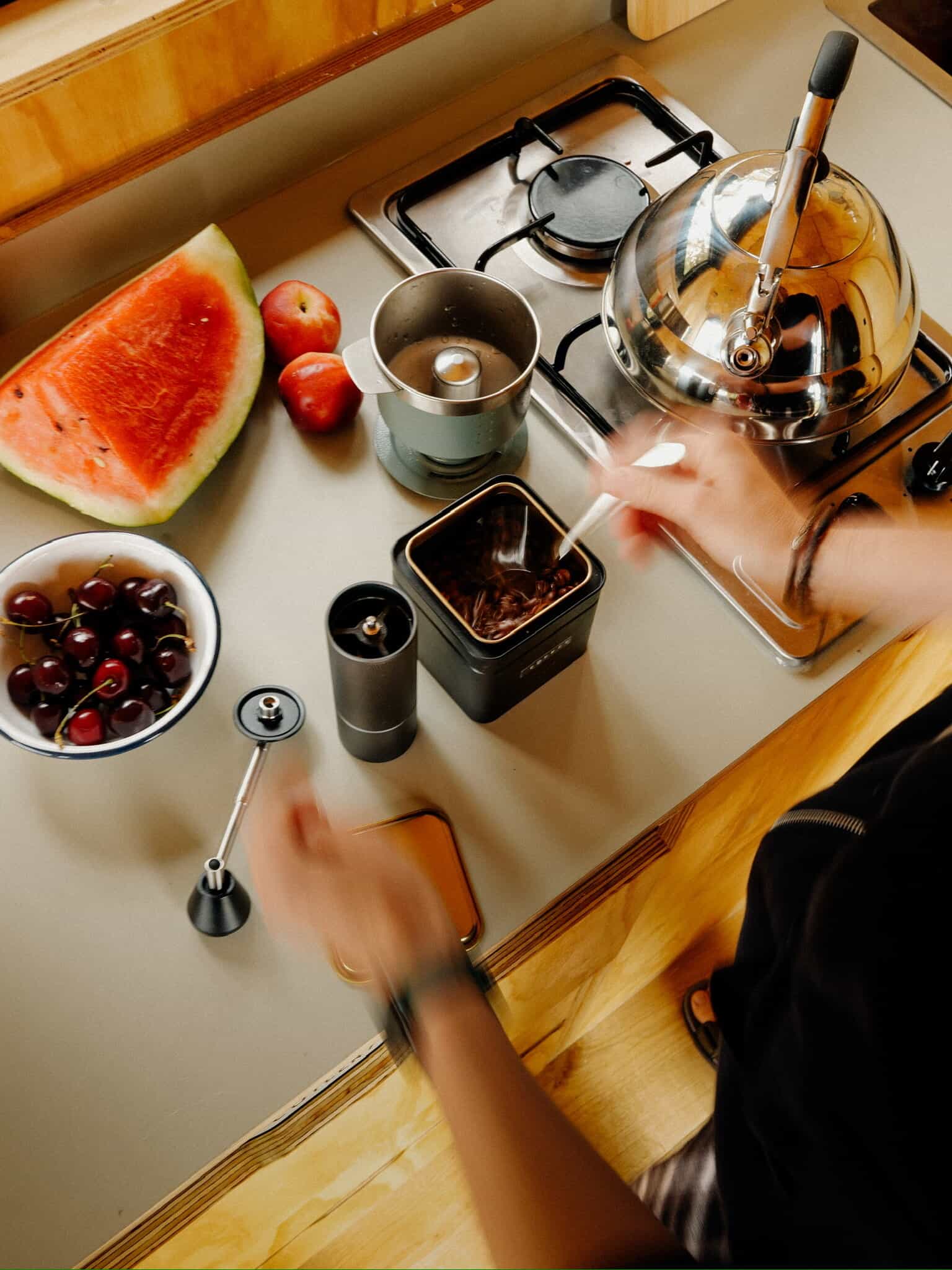 Fresh water melon, apples, cherries, coffee, kettle, and toaster on a tiny off grid kitchen counter for sustainable living.
