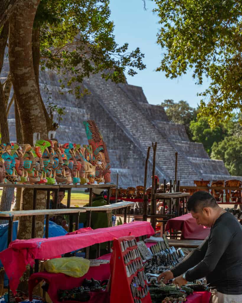 A vendor selling various handmade masks in front of Chitchen Itza