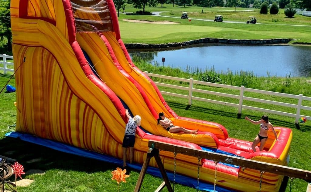 kids playing on a bounce house and water slide rental from Book-N-Bounce STL