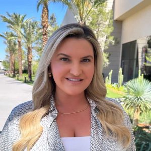 A professional woman with blonde hair outdoors in a sunny garden setting, promoting brain performance and wellness solutions offered by Brain Performance Technologies.