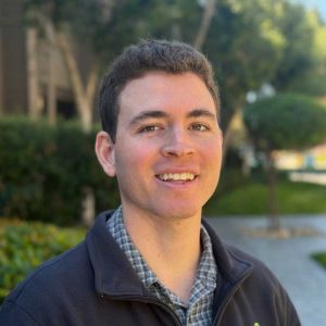 A young man smiling outdoors, illustrating improved brain function and mental clarity through Brain Performance Technologies’ innovative solutions.