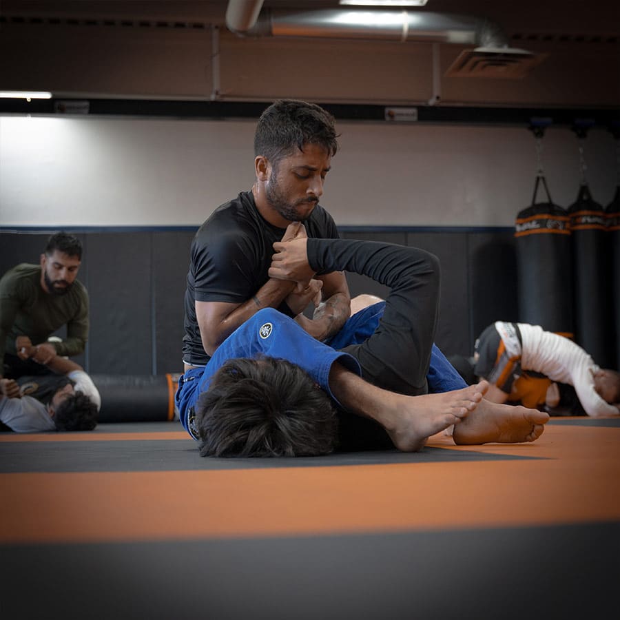 Grappling training at Bravé MMA and Fitness, showcasing Brazilian Jiu-Jitsu techniques in a gym setting.