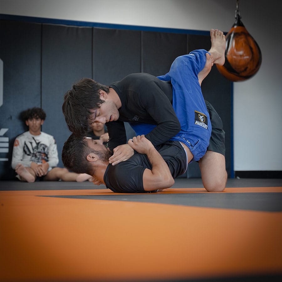 Intense Brazilian Jiu-Jitsu training session at Bravé MMA and Fitness. Students practice grappling and submission techniques.