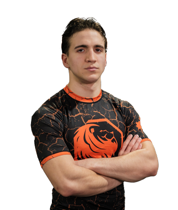 Luca Martinez wearing a black and orange esports jersey with a lion logo, standing confidently with arms crossed.