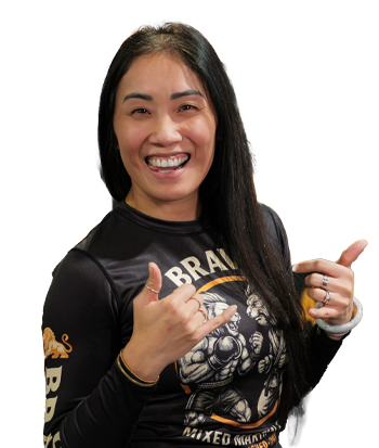 Woman smiling and giving thumbs up, wearing a black graphic t-shirt, in a lively indoor setting.