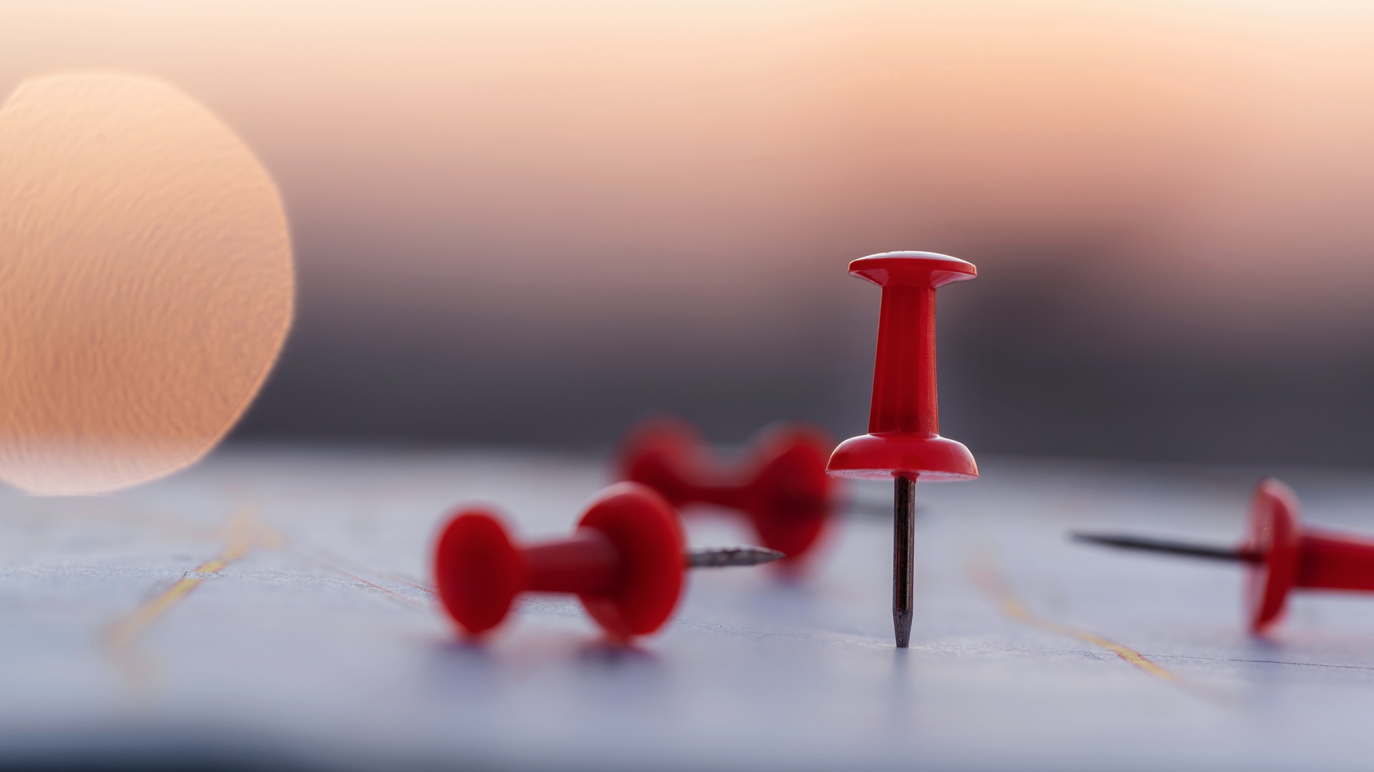 Close up red pin push map under sunset background. business focus and target concept.