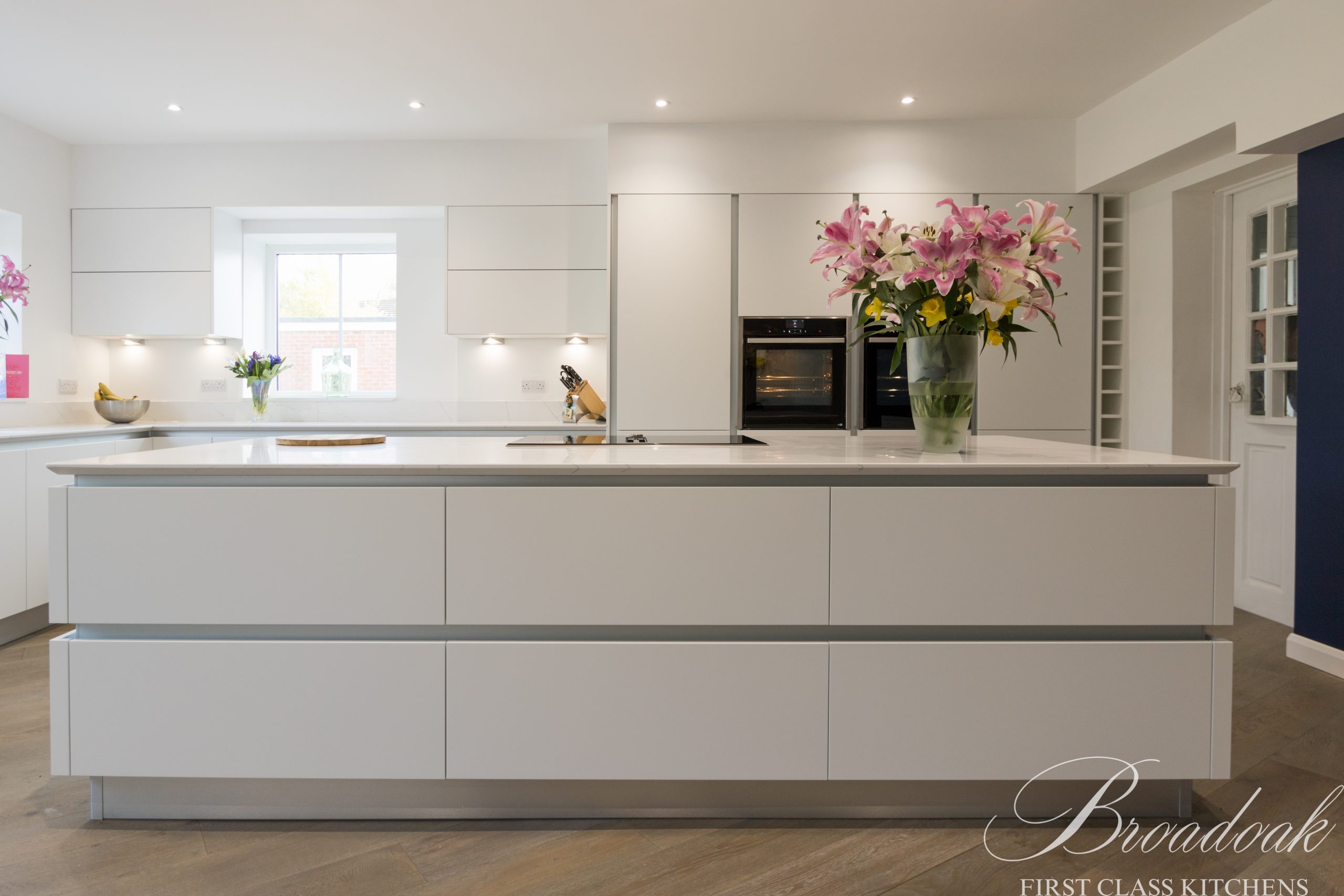 Contemporary white kitchen with a large island and sleek cabinetry by Broadoak Kitchens Ltd, perfect for modern home interiors and premium kitchen renovations.