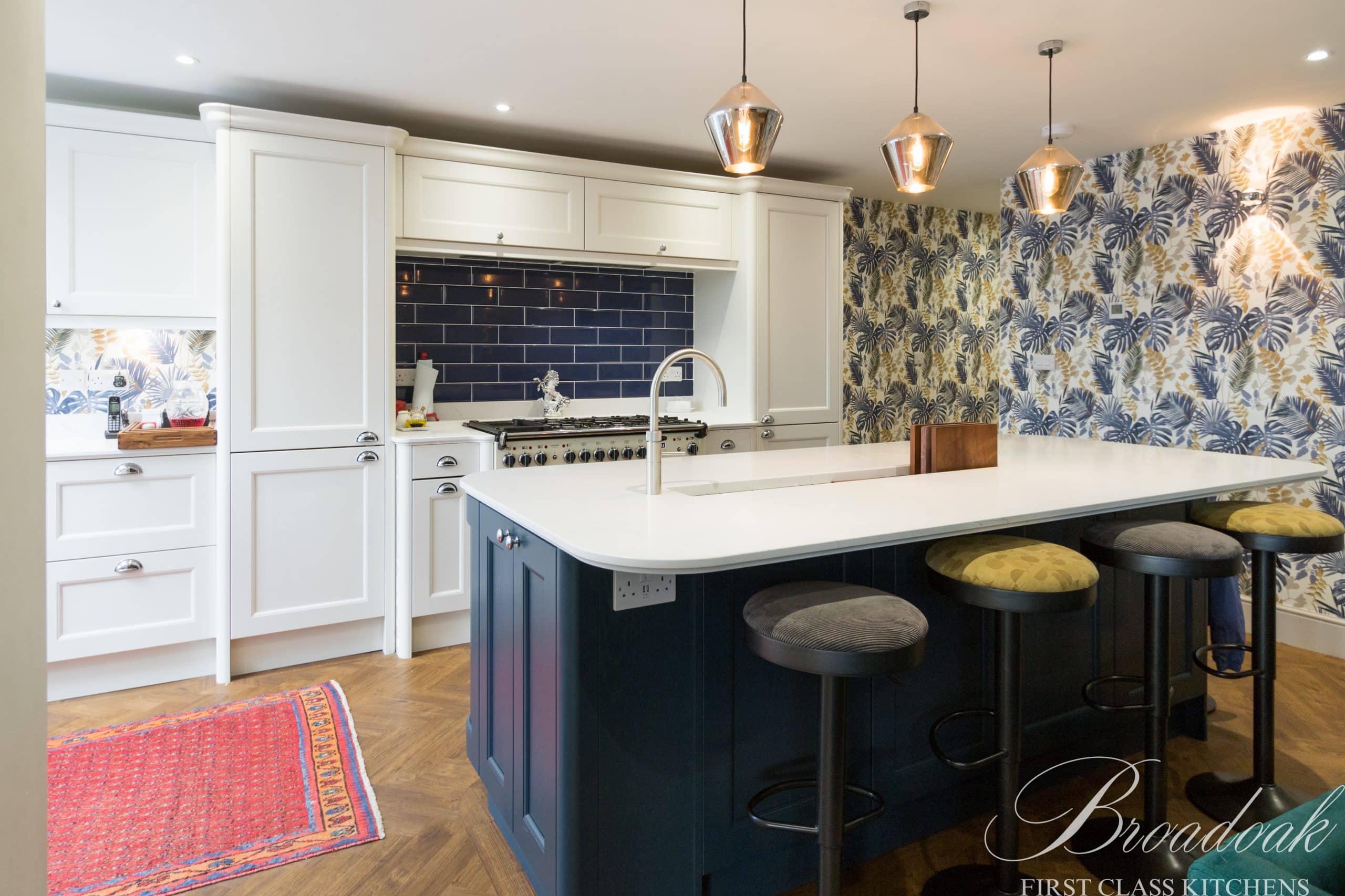 Modern bespoke white and navy kitchen with island, black backsplash, and feature wallpaper, designed by Broadoak Kitchens Ltd, combining style and functionality for luxury home interiors.