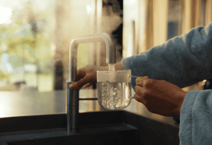 Boiling water being poured from a kettle into a mug on a kitchen countertop, highlighting modern kitchen design and high-quality kitchen appliances by Broadoak Kitchens Ltd.