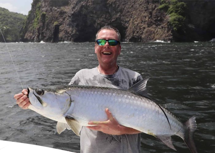 fisherman smiles while holding tarpon in trinidad