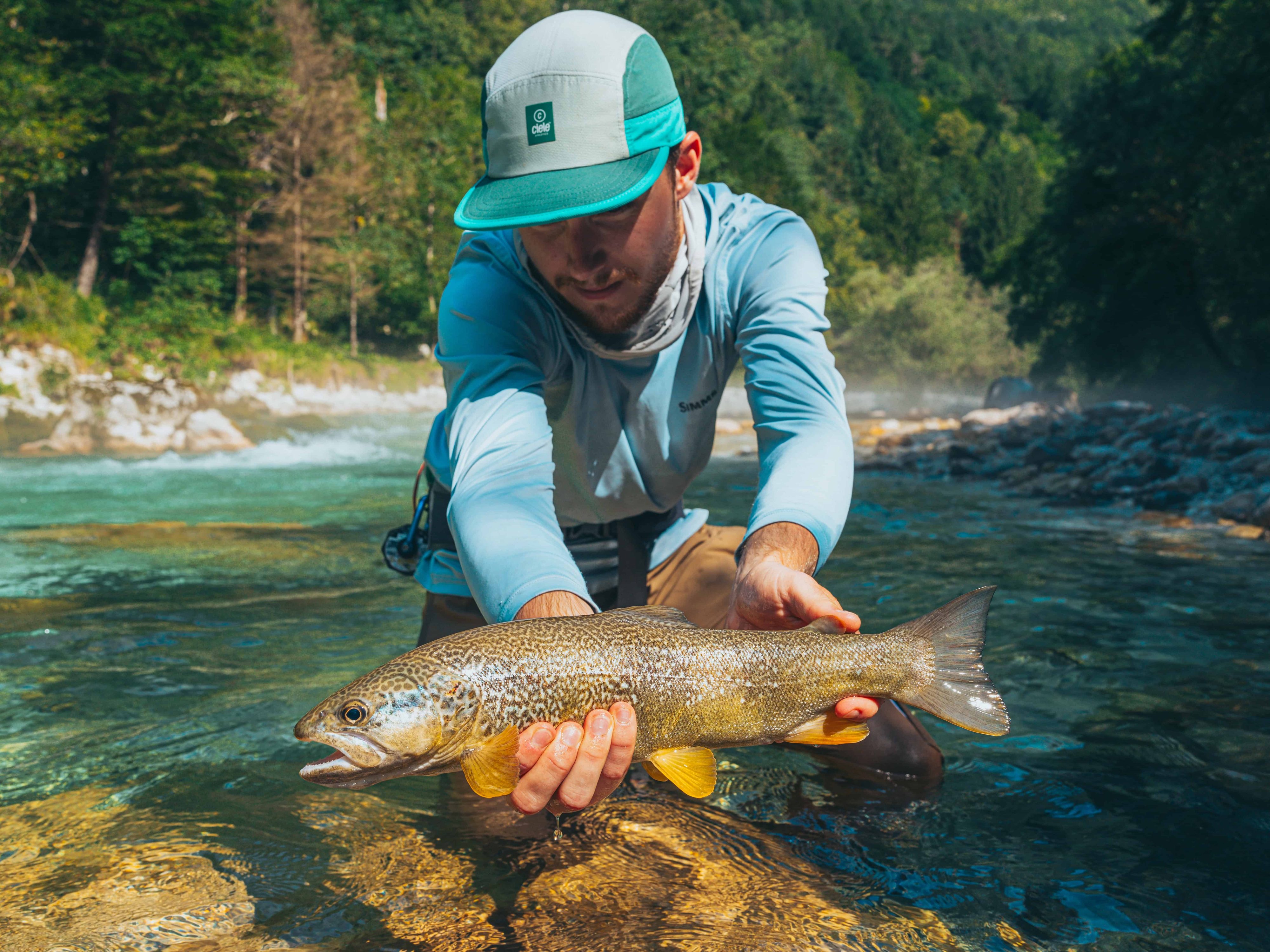 angler posing with a marble trout in a slovenian stream