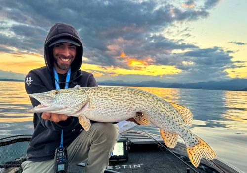 fisherman poses with italian pike on lake garda