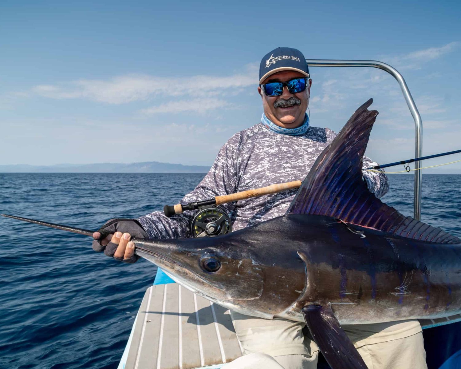 Fly fisherman holding a marlin caught in baja mexico
