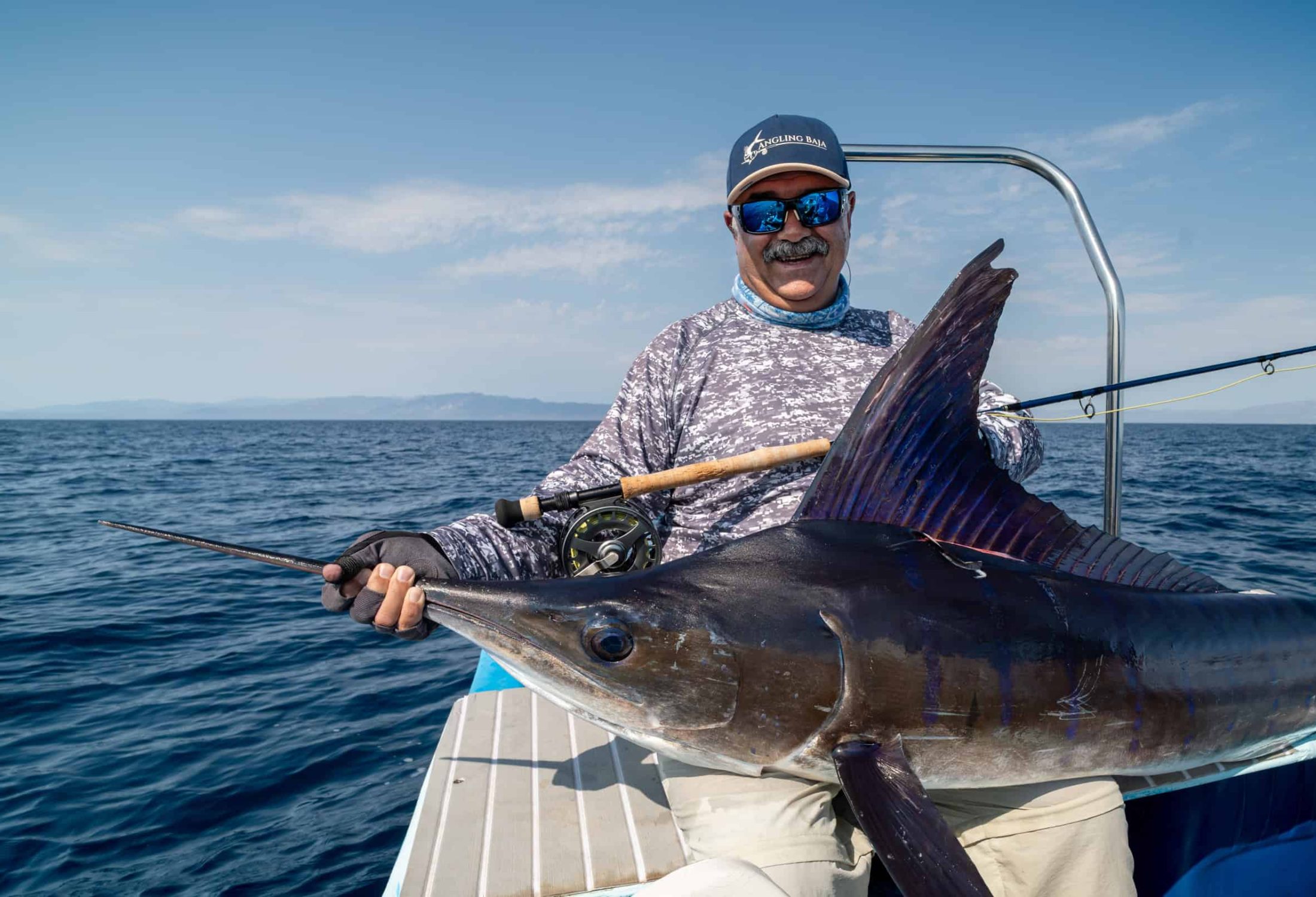 Fly fisherman holding a marlin caught in baja mexico