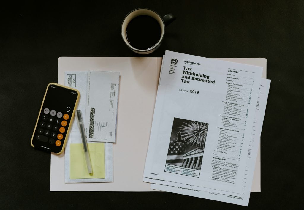 A workspace with tax documents, calculator, pen, and coffee, representing business and tax preparation services for entrepreneurs, accountants, and small businesses.