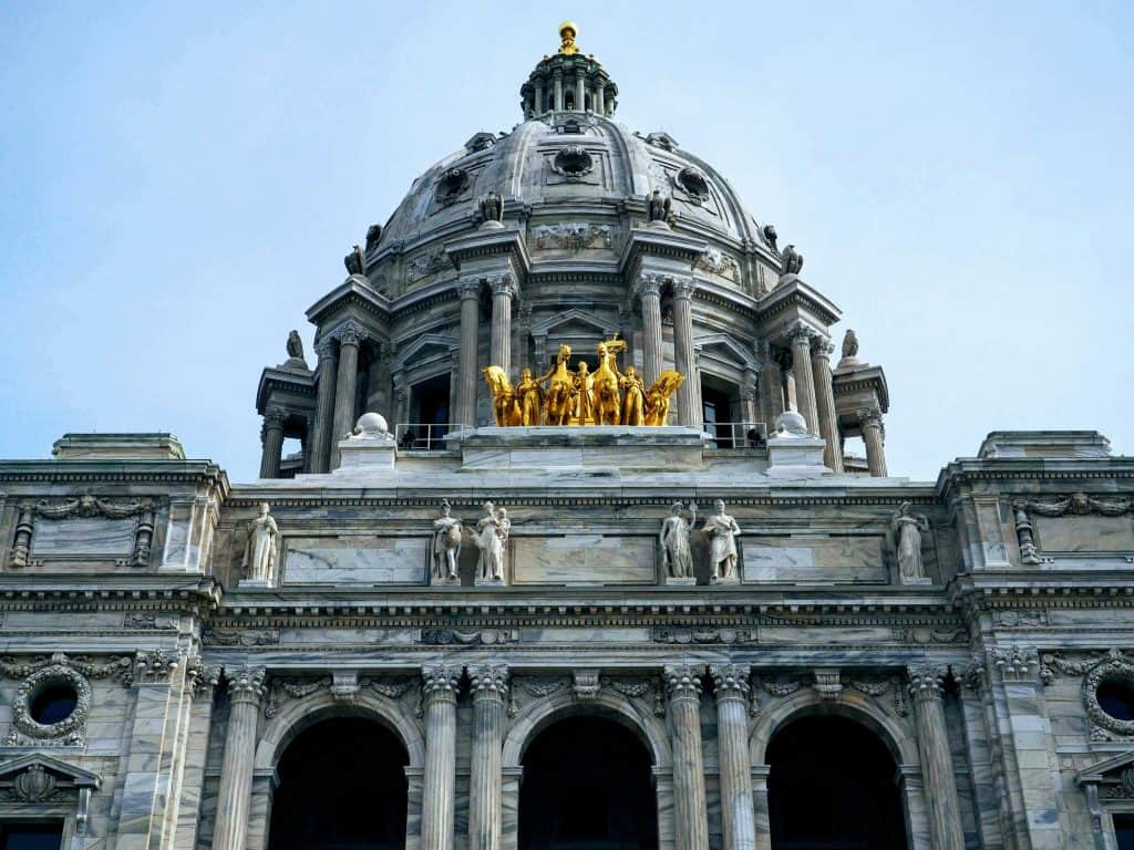 A stunning photo of a historic European-style government or cultural building with intricate stonework, columns, and a grand dome topped with a golden finial, showcasing classic architecture.