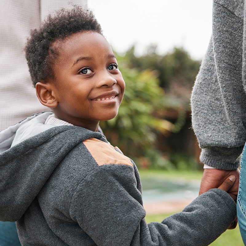 Shot of an adorable little boy holding his parents hands while walking together outdoors