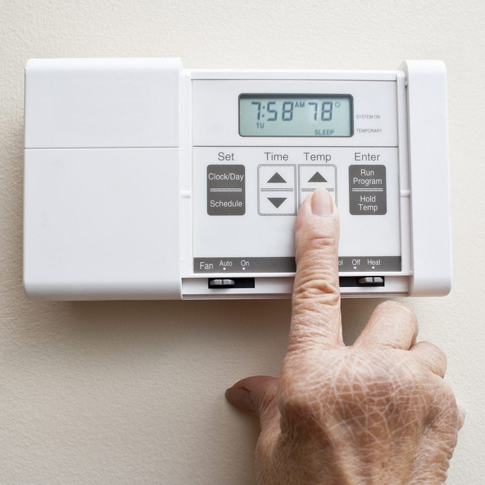 Someone pressing the button to turn down the thermostat