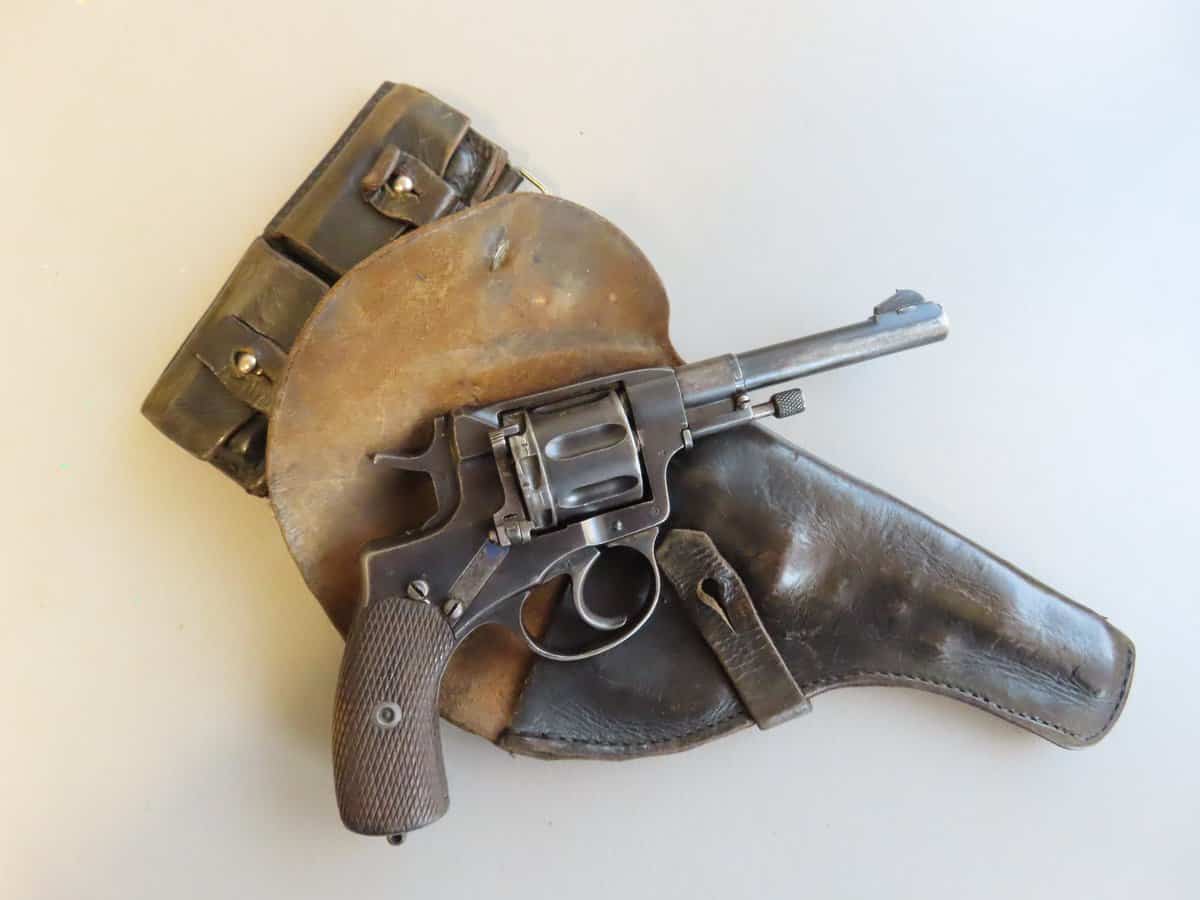 High-quality image of a vintage Colt revolver, leather holster, and ammunition belt showcasing antique firearm accessories.