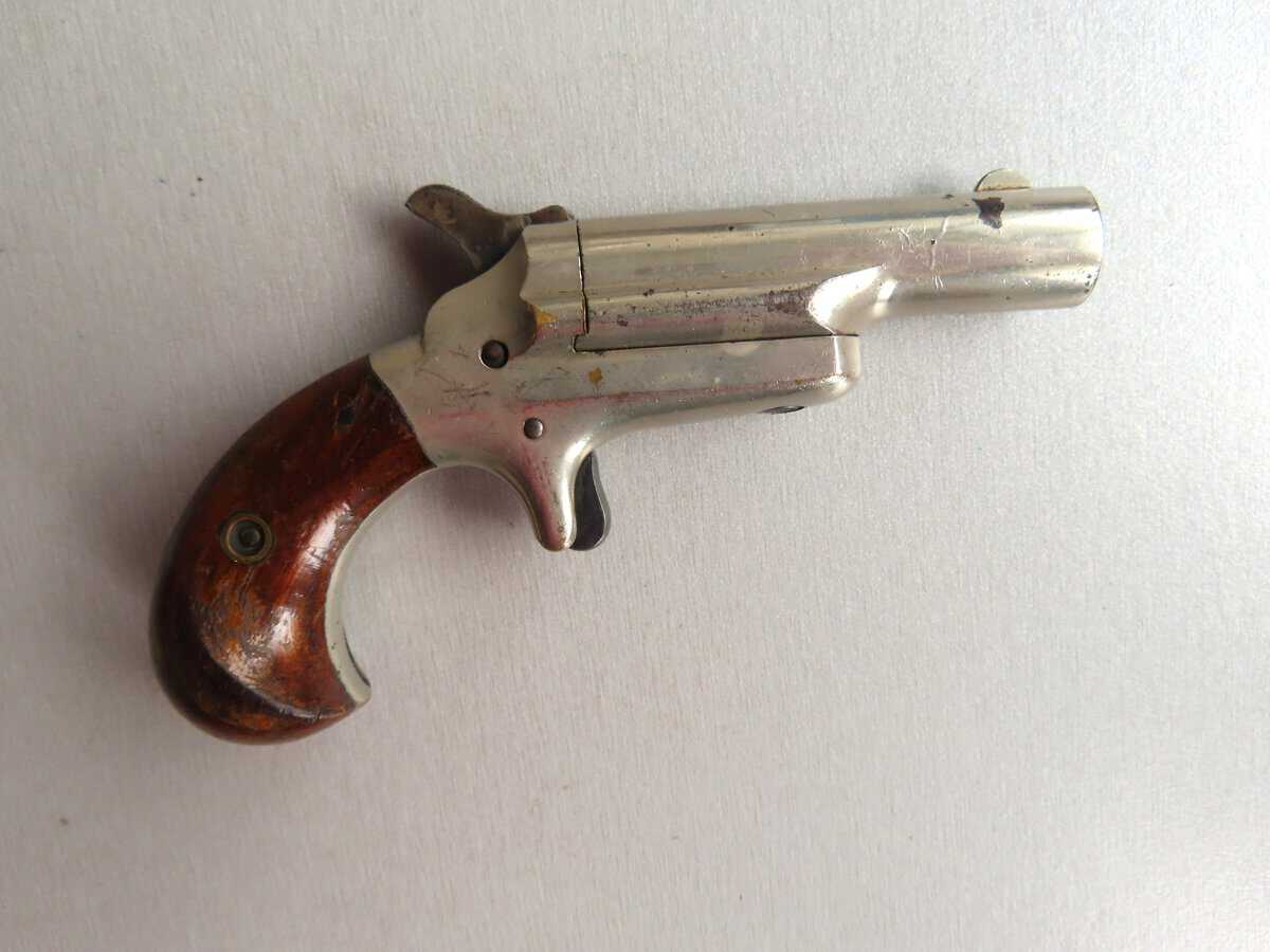 Vintage revolver with wooden handle and silver metal finish, antique firearms collection.