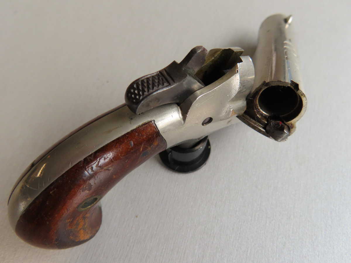 Old revolver handgun with wooden grip and metal slide, historical firearm collectible.