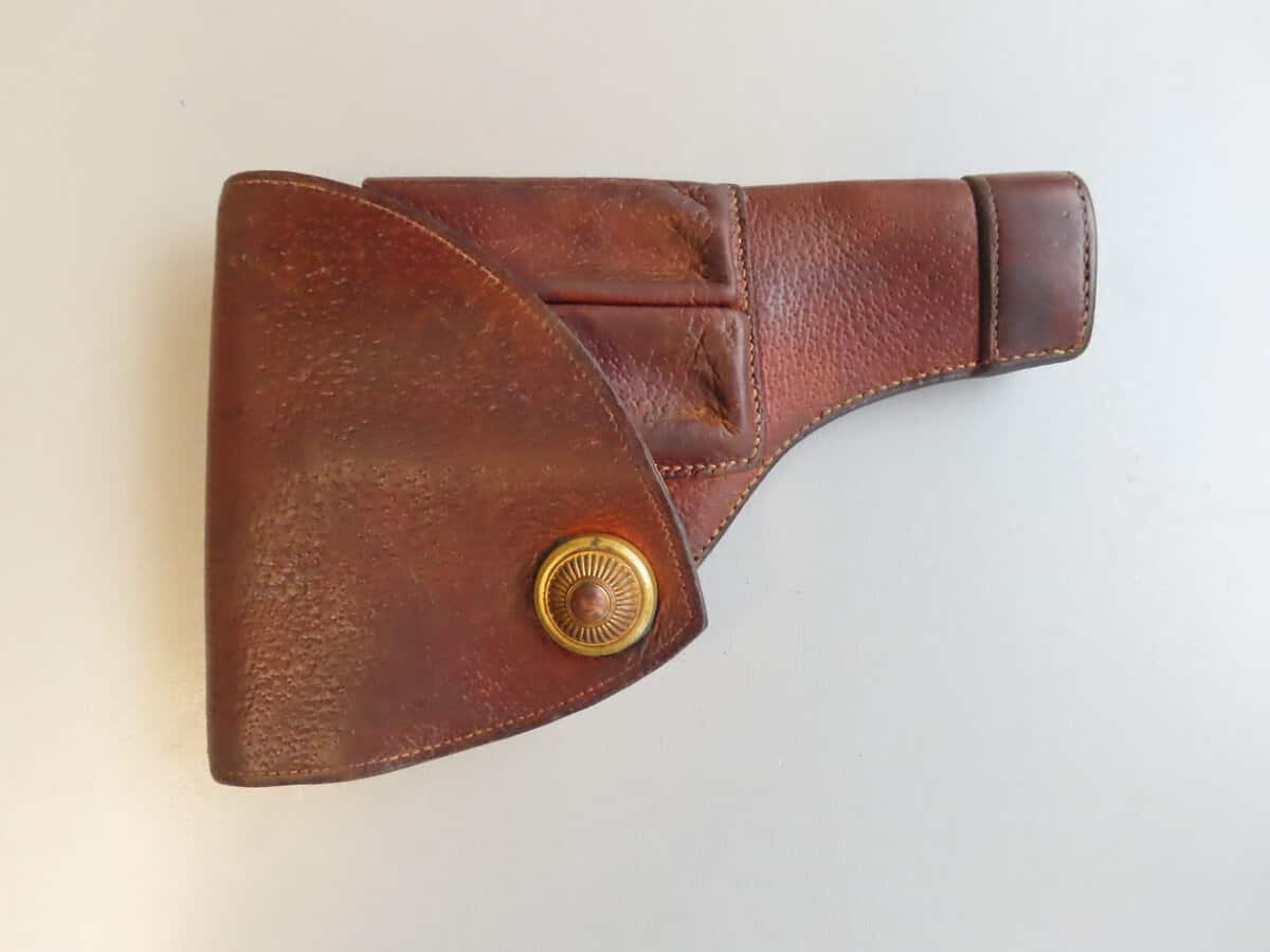 Leather revolver holster with brass button closure, used for safe gun storage. Perfect for collectors and enthusiasts.