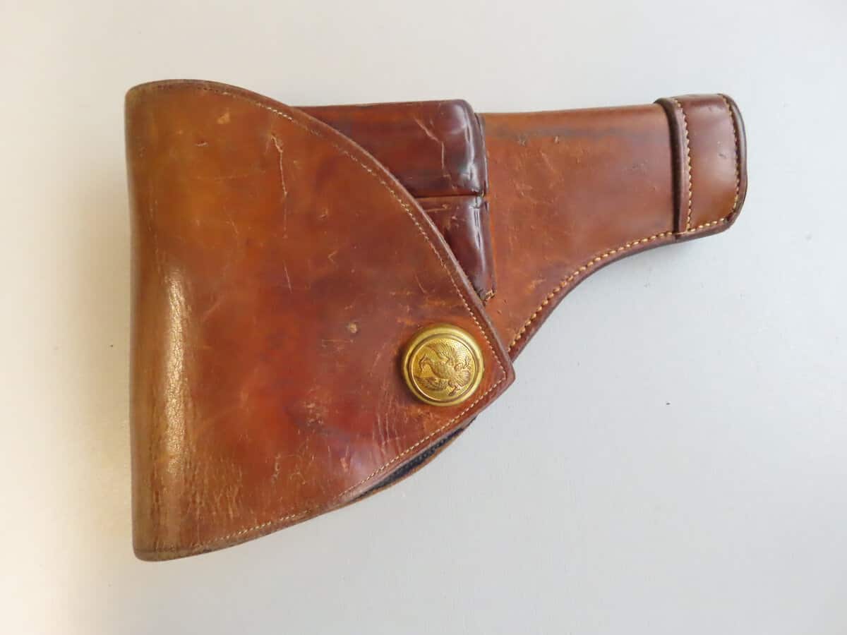 Antique leather gun holster with brass emblem, perfect for firearm collectors.