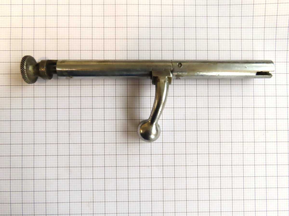 Antique metal gun cleaning tool with handle for ammunition care and firearm maintenance.