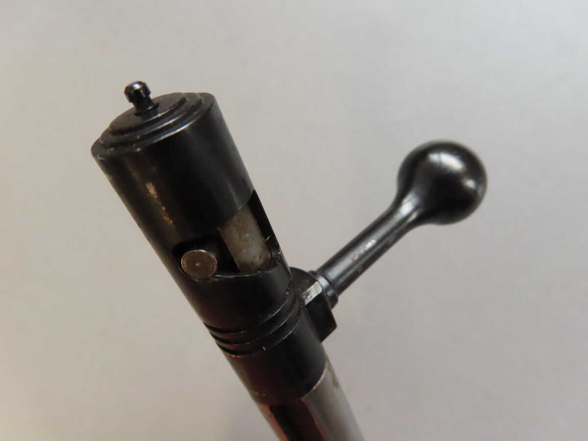 Close-up of a black bolt action firearm handle and mechanism, highlighting vintage ammunition components.