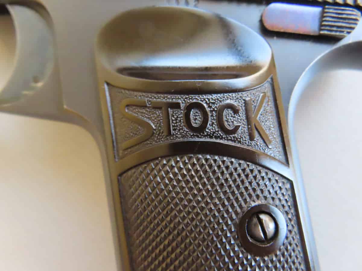 Close-up of textured metal grip with "Stock" logo from Colonial Ammunition Company.