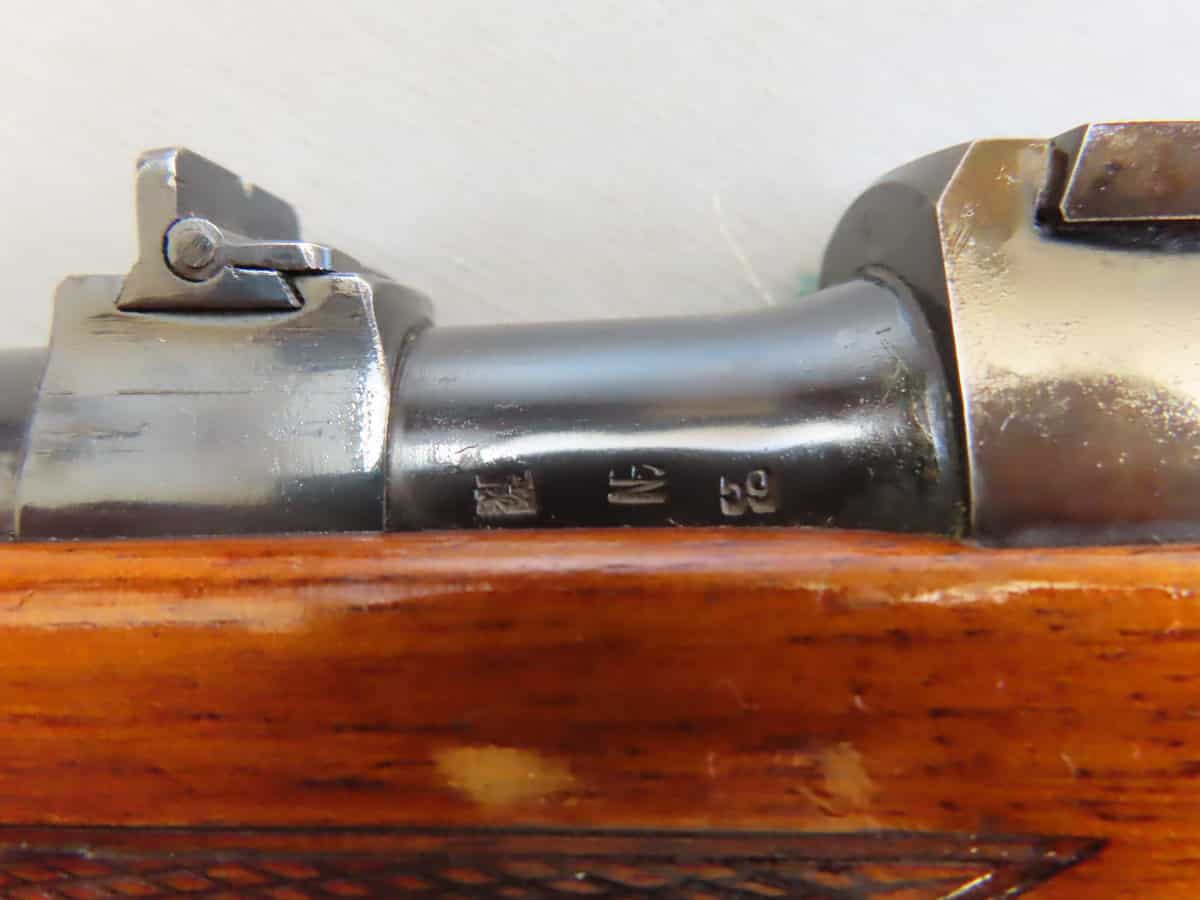 Close-up of a bolt action rifle's mechanism showing metal parts and wooden stock, popular in hunting and firearms collections.