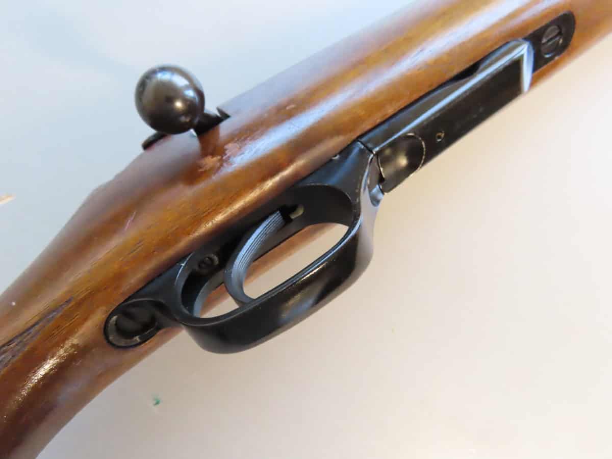 Antique wooden rifle stock with metal trigger and bolt, classic firearm accessory.