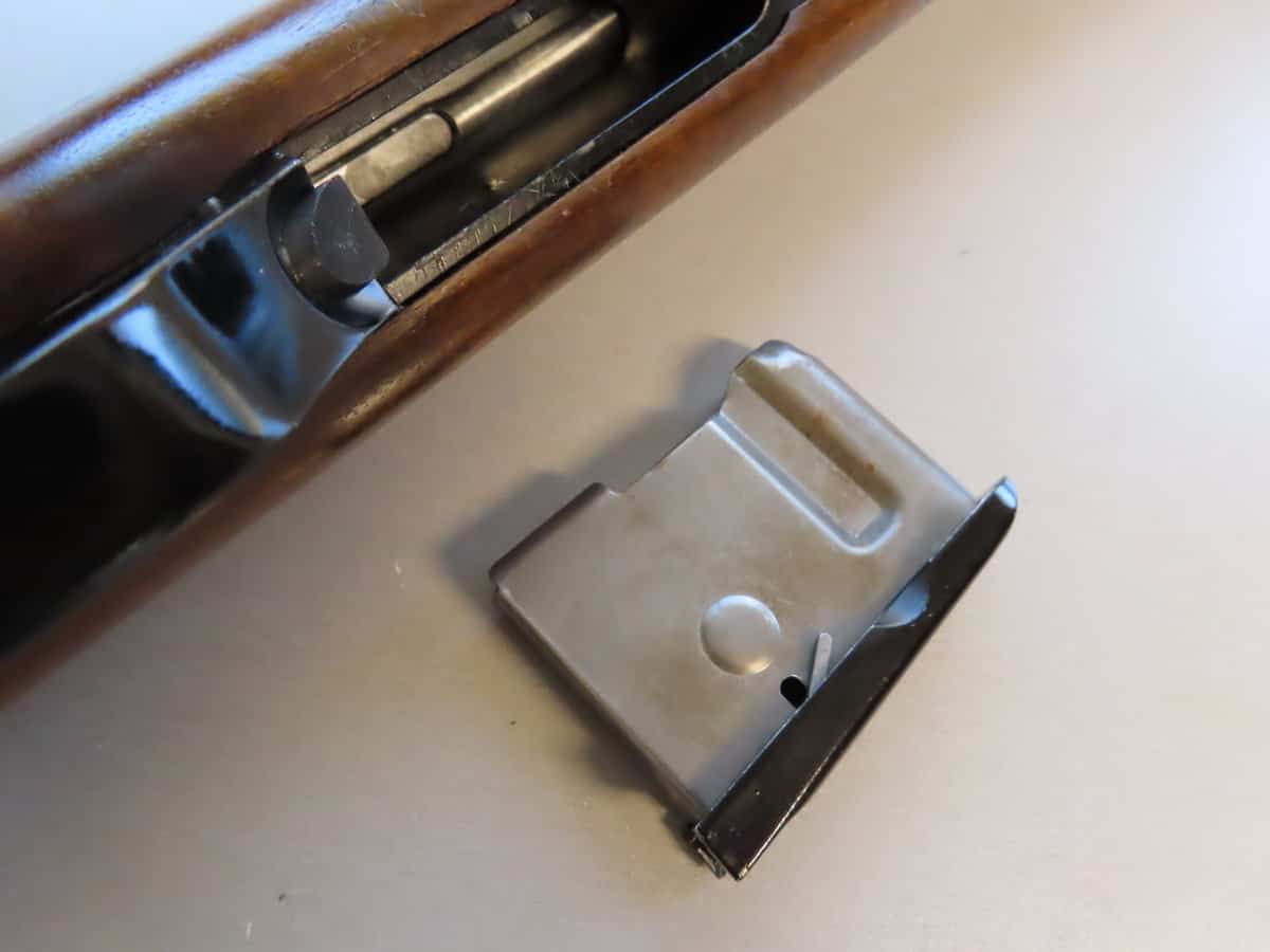 Close-up of vintage rifle with bolt action and removed magazine, showcasing firearm components.