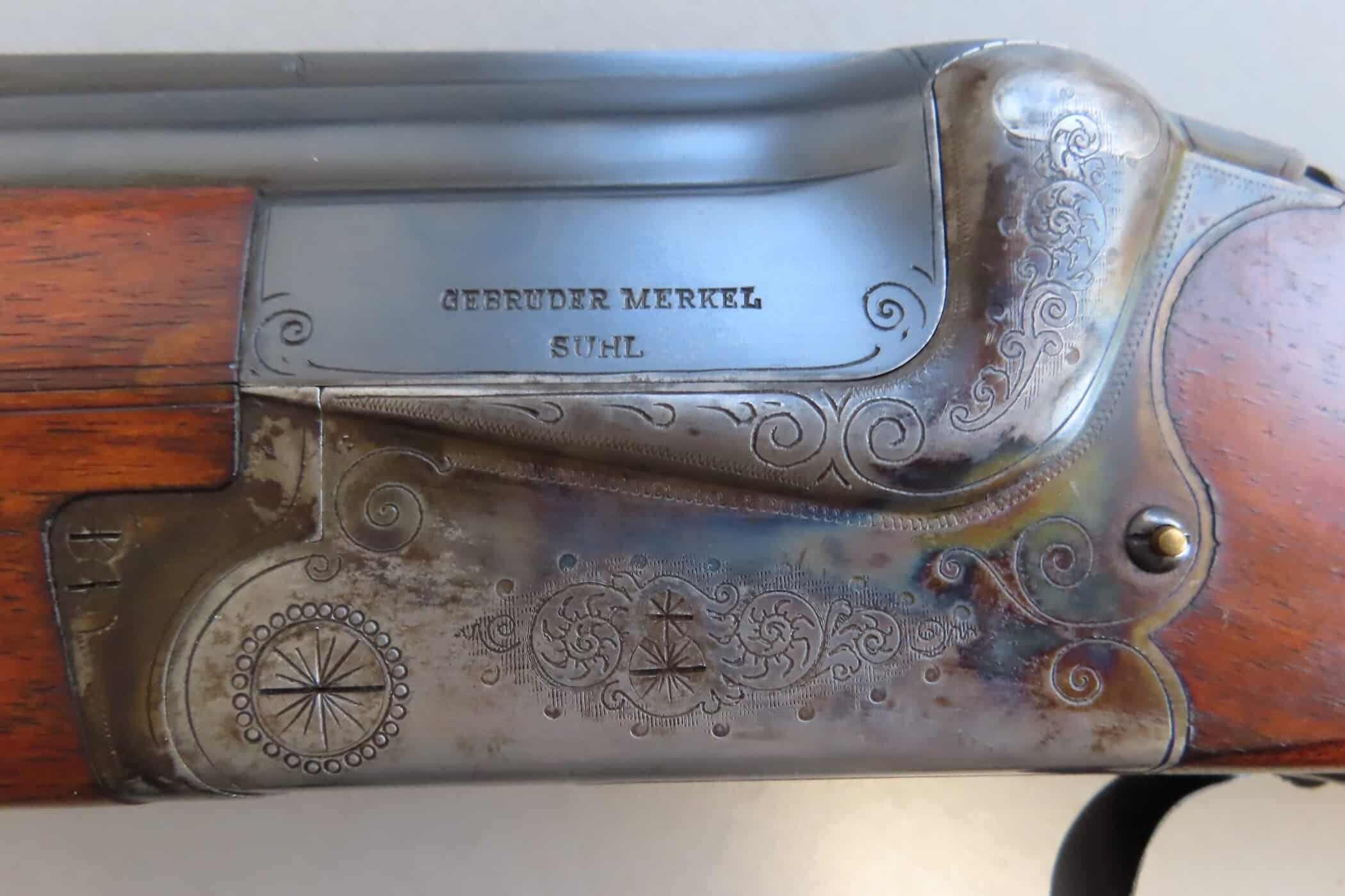 Alt text: Close-up of a vintage firearm engraved with intricate patterns and names.