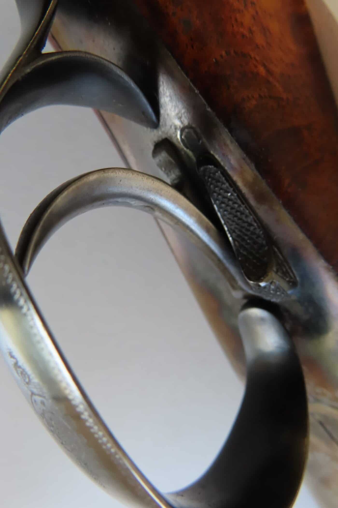 Close-up of a classic firearm trigger with metal and wood finish.