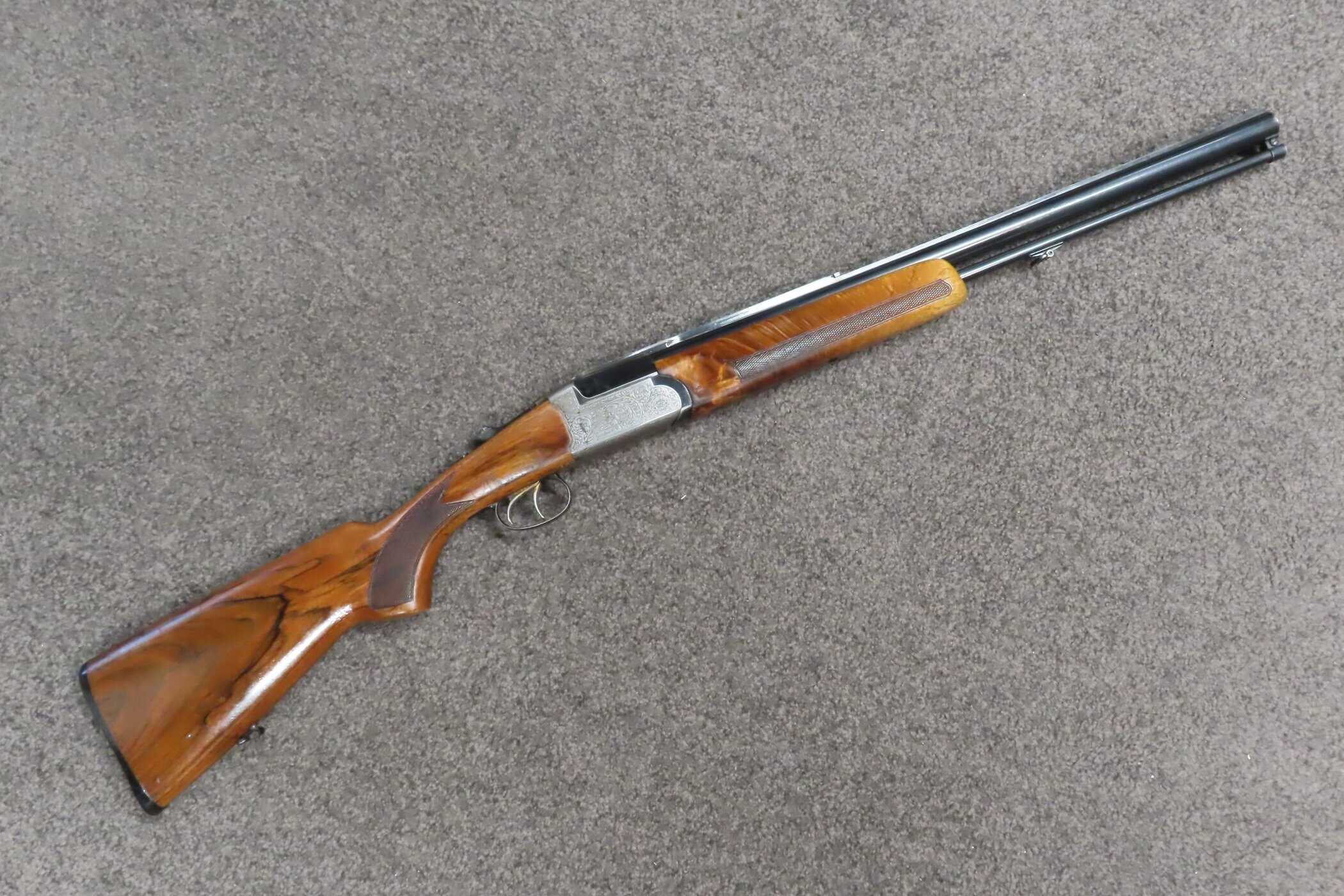 Old fashioned double-barrel shotgun with wooden stock and metal barrels, used for hunting and shooting sports.