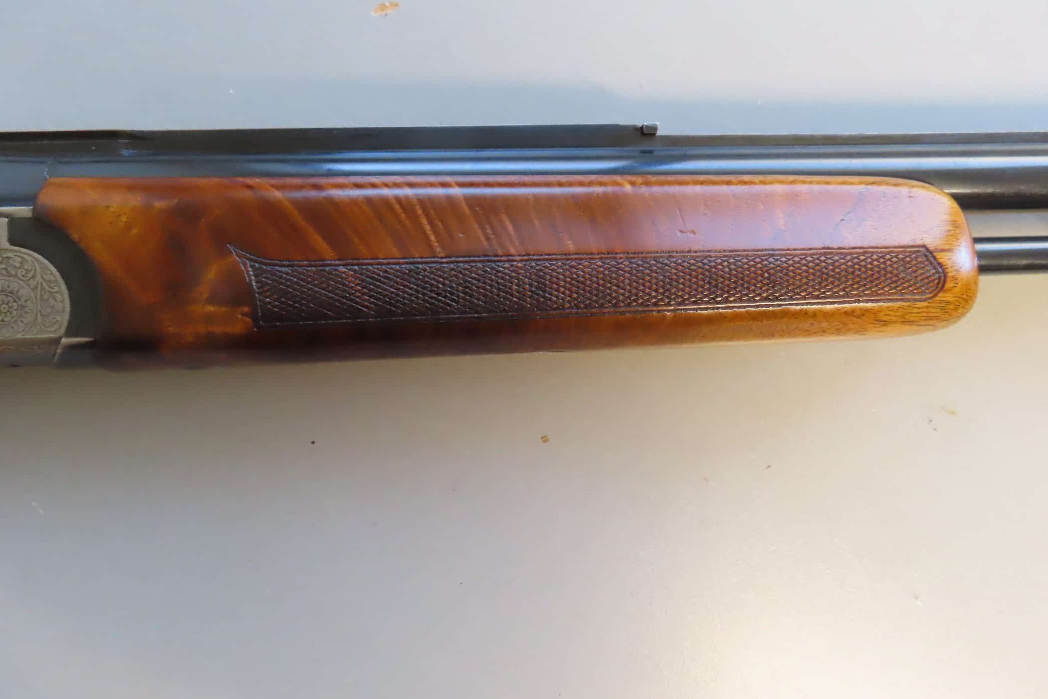 Close-up of a classic rifle stock with detailed checkering and polished wood, representing quality firearms from Colonial Ammunition Company.
